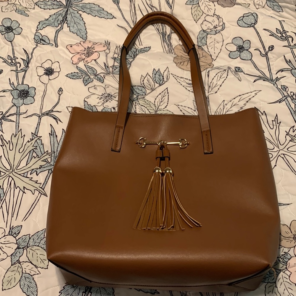 Classic tan faux leather tote with gold tone bit hardware and tassel details.